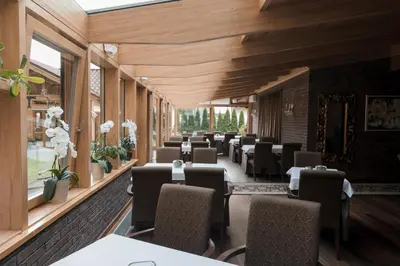 a dining room with tables and chairs and wooden walls at Pušynė in Birštonas