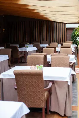 a dining room with tables and chairs with white tables and chairs at Pušynė in Birštonas