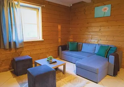 a living room with a blue couch and a table at Sodybos kompleksas - ECO Resort Trakai in Antakalnis