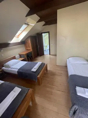 a room with two beds and a wooden floor at Akmenine Kerpe in Marijampolė