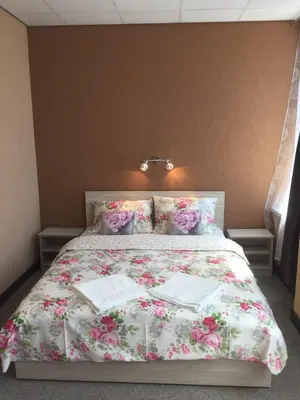 a bed with a floral bedspread and pillows on it at Sveciu Namai- Kazlu Ruda in Kazlų Rūda