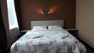 a bedroom with a bed with a floral bedspread and pillows at Sveciu Namai- Kazlu Ruda in Kazlų Rūda