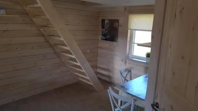 a wooden staircase in a room with a table and a window at Vienkiemis prie Merkinės in Merkinė