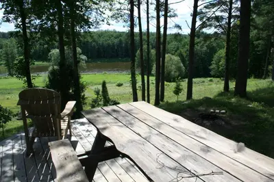 a wooden picnic table and a chair on a patio at Vienkiemis prie Merkinės in Merkinė