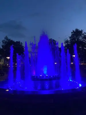 a blue fountain is lit up at night at Cozy Center Apartment in Druskininkai in Druskininkai
