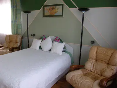 a bedroom with a white bed and two chairs at Home for Guests Lakštingala in Šiauliai