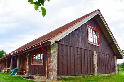 a brown barn with red windows on it at Sunny Beaver B&B in Trakai
