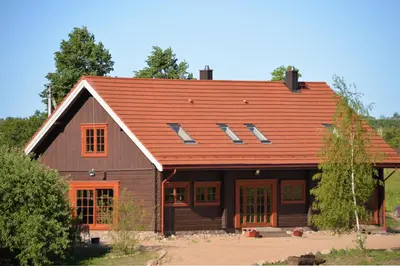 a wooden house with an orange roof at Sunny Beaver B&B in Trakai