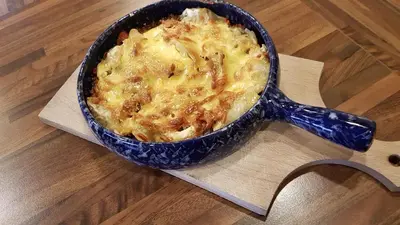 a casserole in a blue pot on a wooden table at Sunny Beaver B&B in Trakai