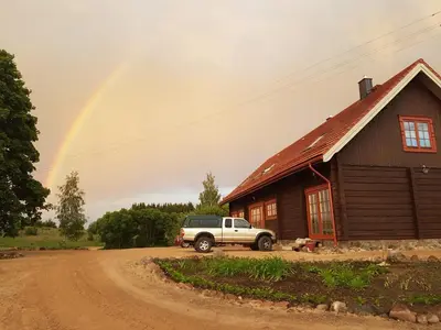 a rainbow over a house with a truck parked in front at Sunny Beaver B&B in Trakai