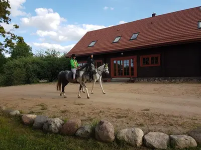 two people riding horses in front of a building at Sunny Beaver B&B in Trakai