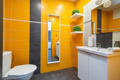 a bathroom with orange walls and a toilet and a sink at Anupro Villa in Trakai