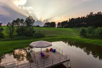 a table with an umbrella and chairs on a dock in a pond at Anupro Villa in Trakai