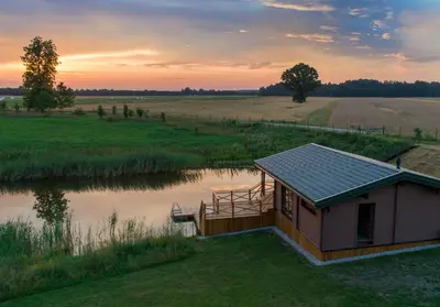 a small cabin in a field next to a lake at Harmony Park Countryside Villas & SPA in Prienai
