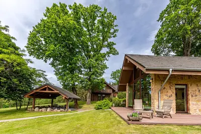 a stone house with a deck and a gazebo at Harmony Park Countryside Villas & SPA in Prienai