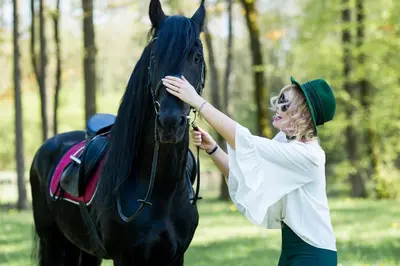 a woman is petting a black horse in a field at Harmony Park Countryside Villas & SPA in Prienai