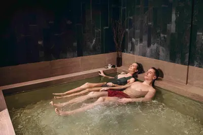 two people sitting in a bathtub in a swimming pool at Vytautas Mineral SPA in Birštonas