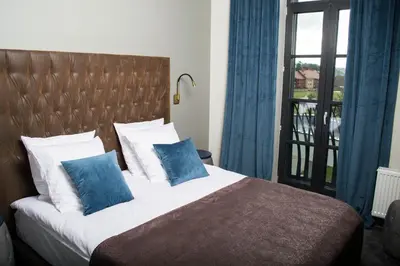 a bedroom with a bed with blue pillows and a window at Vytautas Mineral SPA in Birštonas
