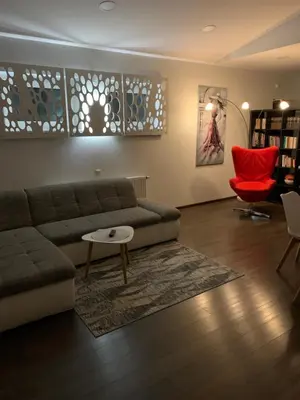 a living room with a couch and a red chair at Apartamentai Fortuna in Kaunas