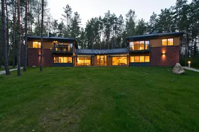 a large house on a grassy field with trees at Ami Residence Forest in Didžiasalis