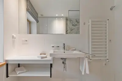 a white bathroom with a sink and a mirror at Ami Residence Forest in Didžiasalis