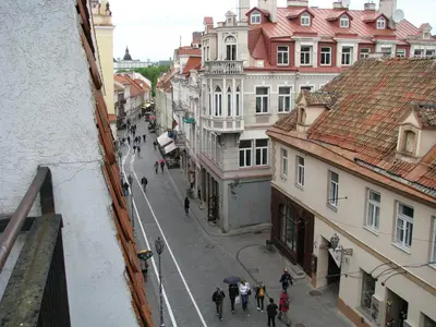 a group of people walking down a street with buildings at Pilies Street Sanctuary Secure Old Town Apartmen in Vilnius