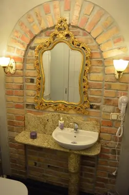 a bathroom with a sink and a mirror on a brick wall at Gabi B&B in Vilnius