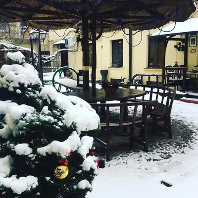 a table and chairs and a christmas tree covered in snow at Gabi B&B in Vilnius