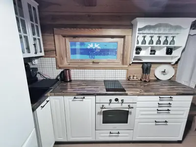 a small kitchen with white cabinets and a stove at Trainiškio pirkia in Ginučiai