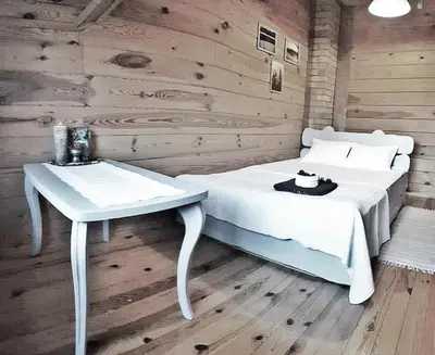 a bedroom with a white bed and a table at Trainiškio pirkia in Ginučiai