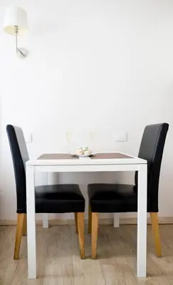 a white dining room table with two black chairs at Cozy studio in Old Town by URBAN RENT in Vilnius