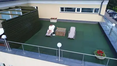 a woman sitting in a chair on a balcony at Aqua Center Apartments in Druskininkai