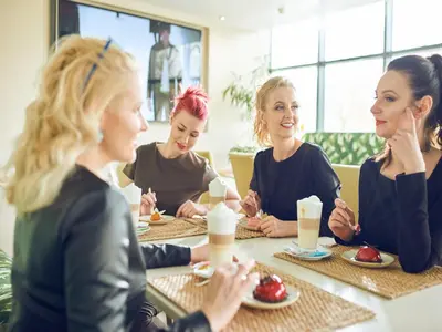 a group of women sitting around a table in a restaurant at Aqua Center Apartments in Druskininkai