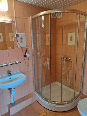 a shower with a glass door next to a sink at Jeruzale Hotel in Vilnius