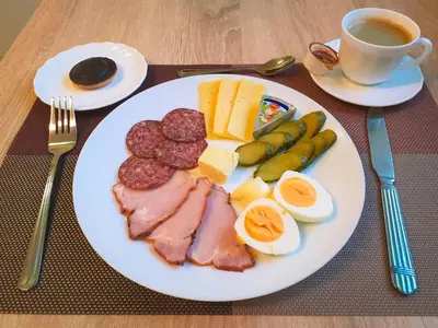 a plate of food with meat and cheese and a cup of coffee at Jeruzale Hotel in Vilnius