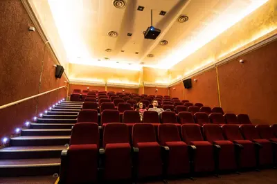 an empty auditorium with red chairs and a person sitting in it at Royal SPA Residence in Birštonas