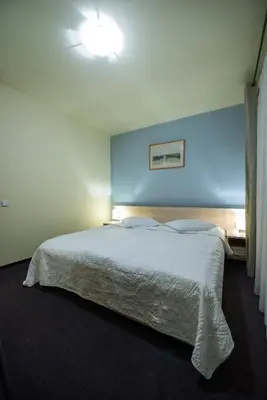 a bedroom with a white bed with a blue wall at Hotel Audenis in Birštonas