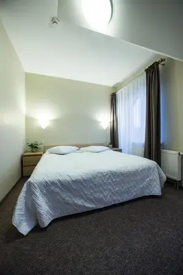 a bedroom with a white bed and a window at Hotel Audenis in Birštonas