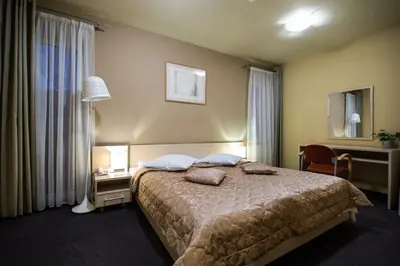a bedroom with a bed and a desk and a lamp at Hotel Audenis in Birštonas