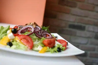 a salad on a white plate on a table at Hotel Audenis in Birštonas