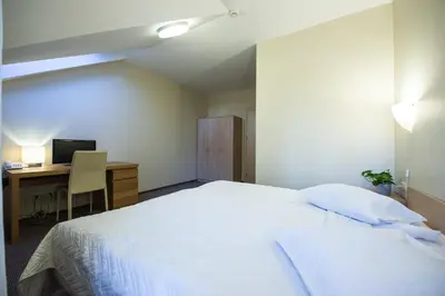 a bedroom with a bed and a desk with a computer at Hotel Audenis in Birštonas