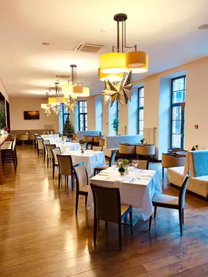 a restaurant with white tables and chairs and windows at VICTORIA Hotel Kaunas in Kaunas