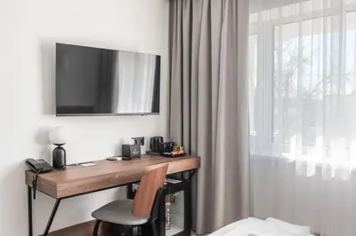 a room with a desk with a television on the wall at AIRINN Vilnius Airport Hotel RENOVATED 2025 in Vilnius