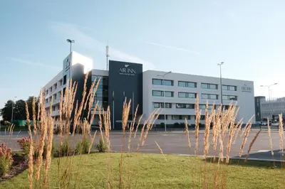 a large building with tall grass in front of it at AIRINN Vilnius Airport Hotel RENOVATED 2025 in Vilnius