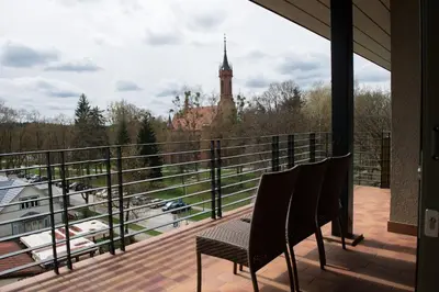 a balcony with two chairs and a clock tower at Grand SPA Lietuva Hotel Druskininkai in Druskininkai