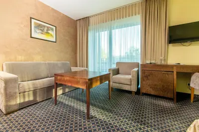 a hotel room with a couch and a table and a tv at Grand SPA Lietuva Hotel Druskininkai in Druskininkai