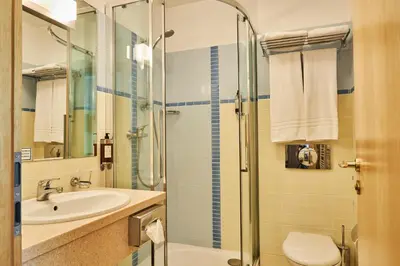 a bathroom with a shower and a sink and a toilet at Grand SPA Lietuva Hotel Druskininkai in Druskininkai