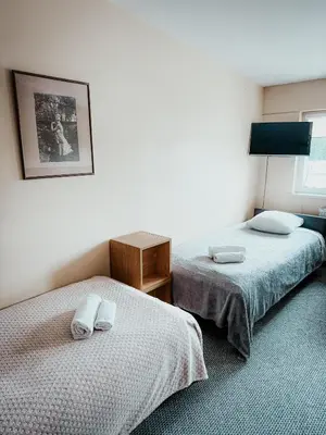 a room with two beds and a table and a picture at Pervaža in Panevėžys