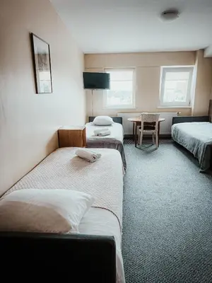 a room with three beds and a table in it at Pervaža in Panevėžys