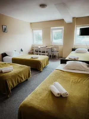 a room with three beds and a table and chairs at Pervaža in Panevėžys
